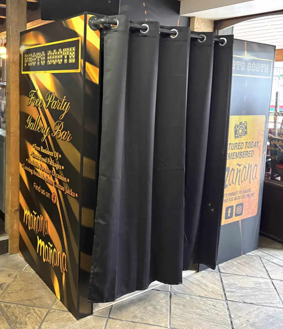 Mañana Mañana black-and-gold photobooth with a curtain and branded side panel