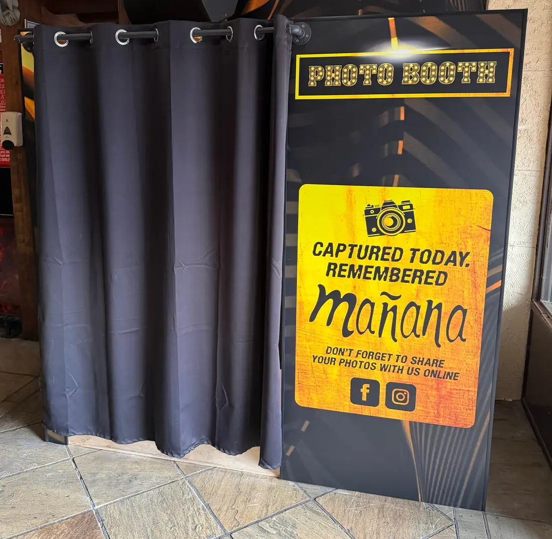 Mañana Mañana photobooth with black curtain and a branded captured today message